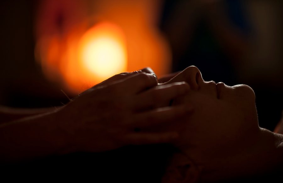 Close-up of a calming facial and scalp massage in warm, dim studio light